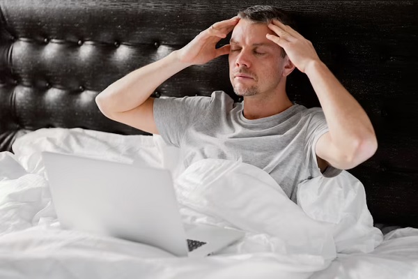 Innsomnio afecta el pelo - Hombre con laptop sobre las piernas enfrenta dificultades para dormir
