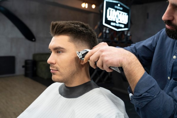 cortes de pelo - joven en la barbería realizándose un corte de pelo moderno