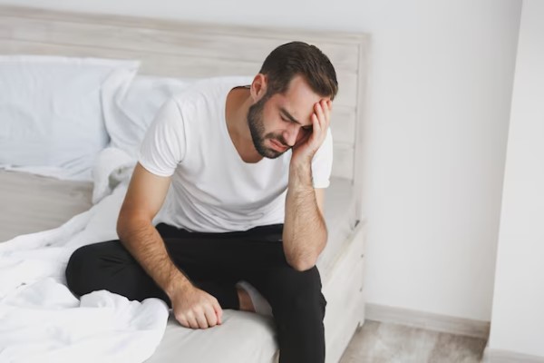 hombre se levanta cansado por que ronca al dormir presentando claros síntomas de calvicie en las entradas
