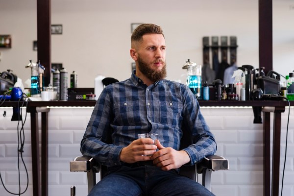 cortes de pelo - hombre sentado en la silla de la barbería con un buen corte de pelo