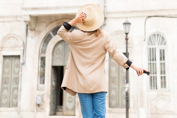 mujer en la calle con una maleta y un sombrero tras el trasplante de cabello