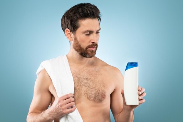 hombre a punto de ducharse llevando un bote de champú para su tipo de cabello