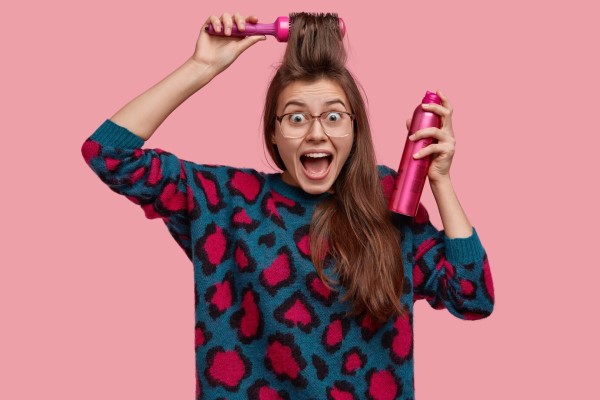 mujer peinándose con un cepillo, lista para usar laca sobre su cabello grasoso
