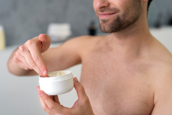 pelo graso - hombre a punto de aplicar cera capilar en su melena, producto que puede aumentar el pelo graso