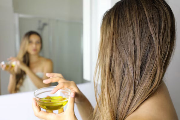 Pelo quemado - Joven frente al espejo aplica una mascarilla capilar hidratante de aceite de oliva