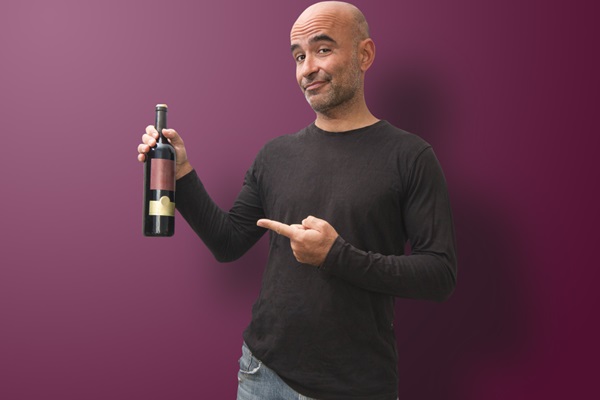 Alcohol en el injerto capilar - Hombre con alopecia sosteniendo una botella de vino con cara de resignación por dejar el alcohol