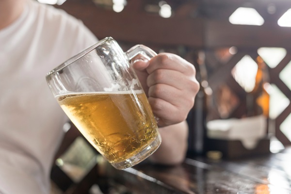 Alcohol en el injerto capilar - Hombre sentado en un bar bebiendo alcohol sosteniendo en su mano un vaso de cerveza