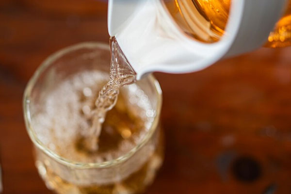Plano cenital de una jarra de trigo fermentado llenando un vaso de vidrio