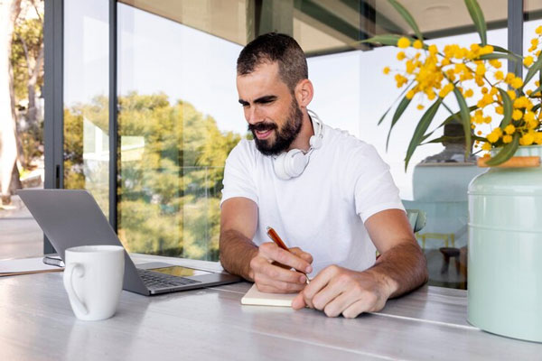 Hombre trabaja desde su computadora mientras sigue todos los cuidados postoperatorios tras un trasplante de cabello