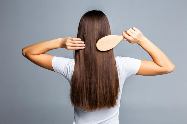 Levadura de cerveza - Joven de espaldas cepilla su cabello largo y abundante