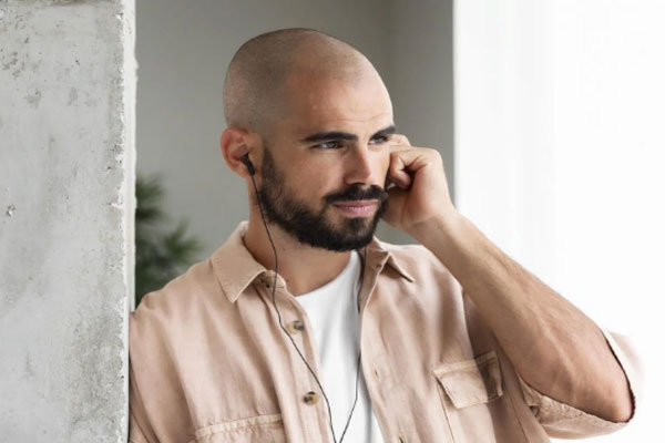 Inflamación tras injerto capilar - Hombre de pelo rapado habla por teléfono mientras se recupera de un trasplante de cabello