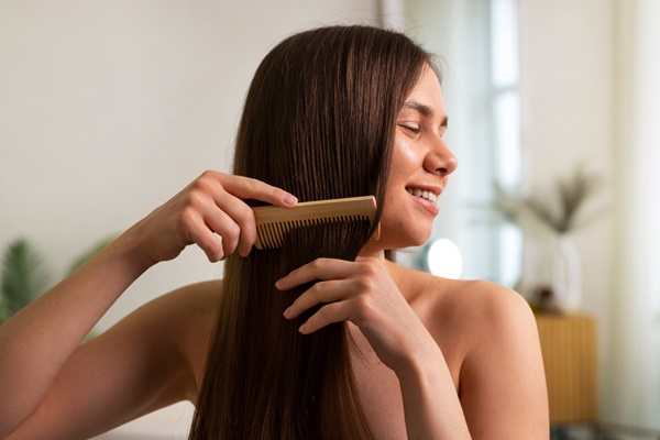 Mujer feliz peinando su pelo liso y brillante con un cepillo de puntas anchas