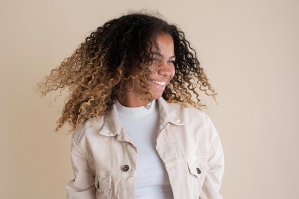 Cerveza para el cabello - Mujer joven sonriente jugando con su cabello rizado de color claro en las puntas