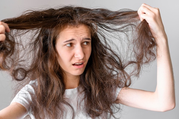 Cerveza para el cabello - Mujer sujetando su pelo seco y apagado debido a los daños causados por no hidratar el cabello adecuadamente