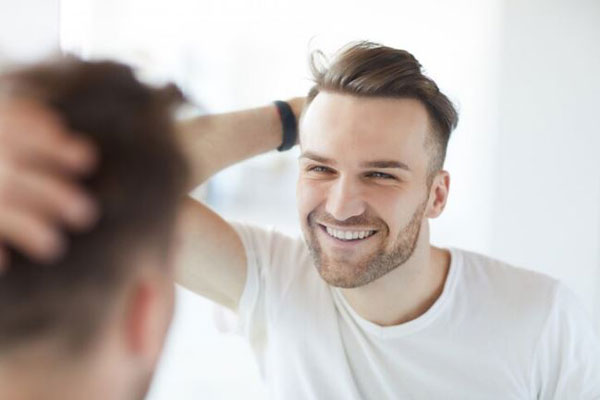 Gimnasio tras injerto capilar - Joven feliz aprecia los resultados de un trasplante de cabello y la recuperación de la densidad capilar 