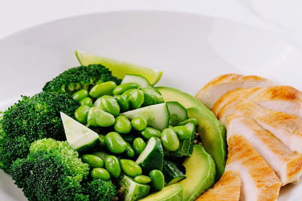 Plano detalle de un plato de pollo y de vegetales de hoja verde ricos biotina para estimular el crecimiento del cabello