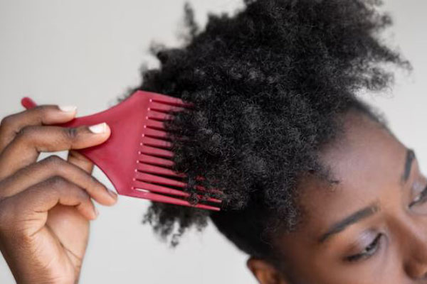 Peinar cada tipo de pelo - Mujer de pelo crespo usa un peine especial para darle forma al cabello