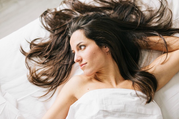 Cómo cuidar el cabello mojado - Mujer acostada en la cama para dormir con el pelo mojado, lo cual provoca bacterias y hongos en el cuero cabelludo