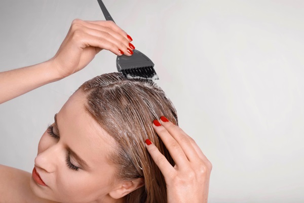 Cómo cuidar el cabello mojado - Mujer de cabello rubio aplicando una mascarilla capilar para nutrir e hidratar el pelo