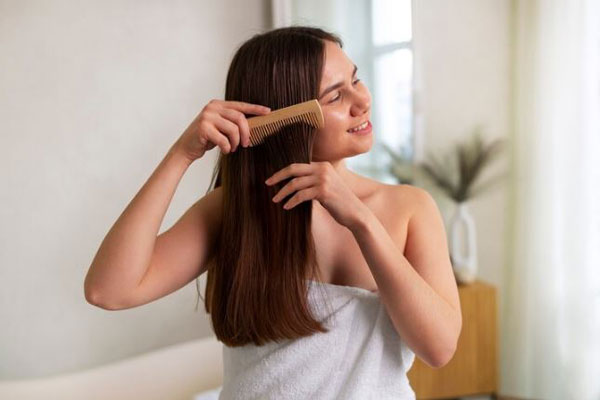 Peinar cada tipo de pelo - Joven de pelo lacio se desenreda el cabello tras salir de la ducha