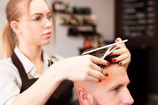 Cortar el cabello - Estilista cortando el cabello de un hombre usando tijeras y un peine
