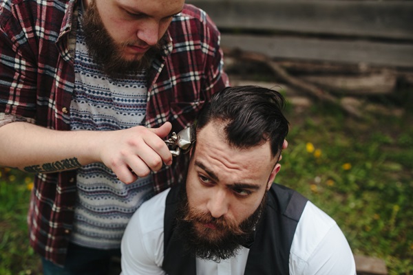 Cortar el cabello - Estilista usando una máquina eléctrica para afeitar el cabello de un hombre con alopecia