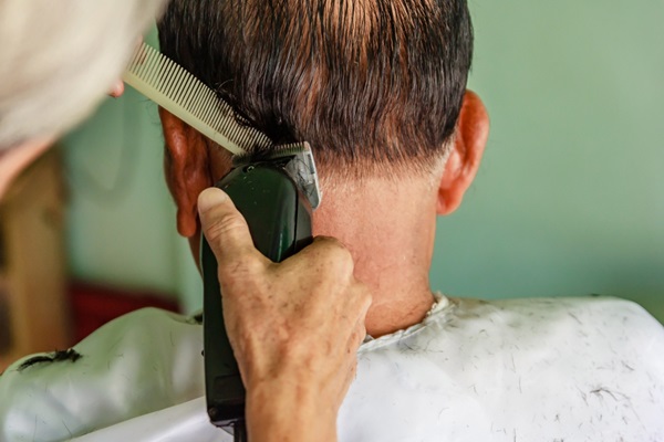 Cortar el cabello - Barbero usando un peine y una máquina de afeitar para crear un corte de cabello clásico a un hombre