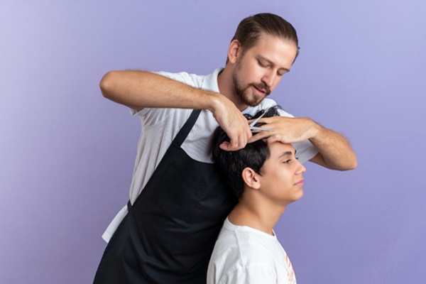 Cortar el cabello - Estilista usando tijeras para cortar el cabello largo de un hombre de manera precisa