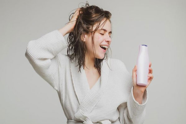 Joven con cabello mojado y con champú en mano disfruta de los beneficios de usar productos capilares de calidad