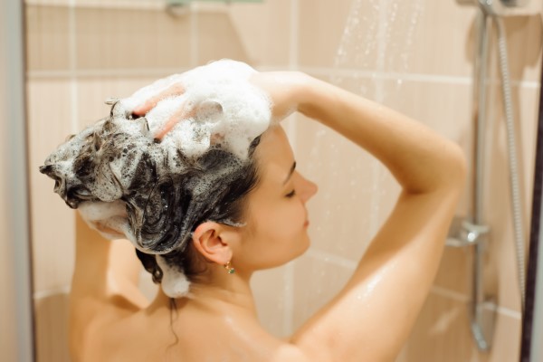 Salud capilar - mujer masajeando su cuero cabelludo durante la ducha para ayudar a mantener su cabello sano