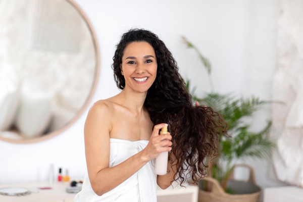 Mujer joven con el pelo rizado aplicándose un tratamiento hidratante para evitar el frizz