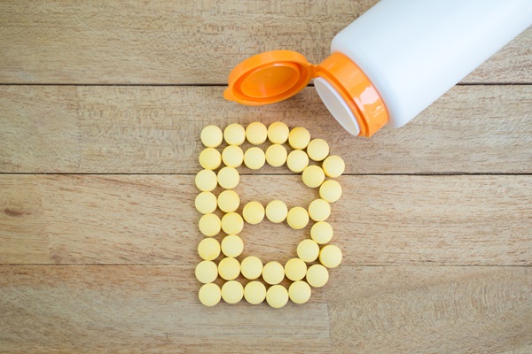 Vitaminas para evitar la alopecia - Recipiente blanco con varias pastillas de vitaminas formando una letra B