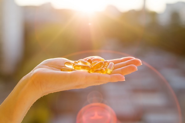 Vitaminas para evitar la alopecia - Persona sosteniendo en su mano varias pastillas de vitaminas frente a los rayos del sol