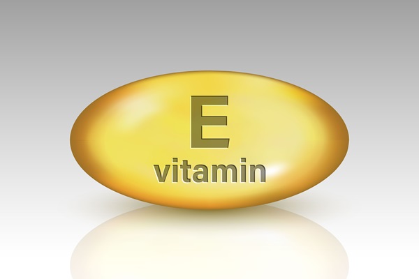 Vitaminas para evitar la alopecia - Pastilla de color amarillo con las letras de Vitamina E para suplemento de nutrientes