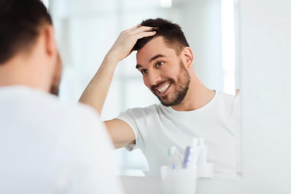 salud capilar - hombre contento mirando en el espejo su cabello sano