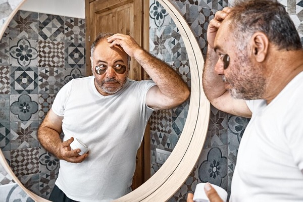Consecuencias psicológicas de la alopecia- hombre que se ocupa de su aspecto f{isico, revisa su alopecia frente al espejo