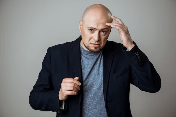 Consecuencias psicológicas de la alopecia- hombre con traje toca su cabeza calva