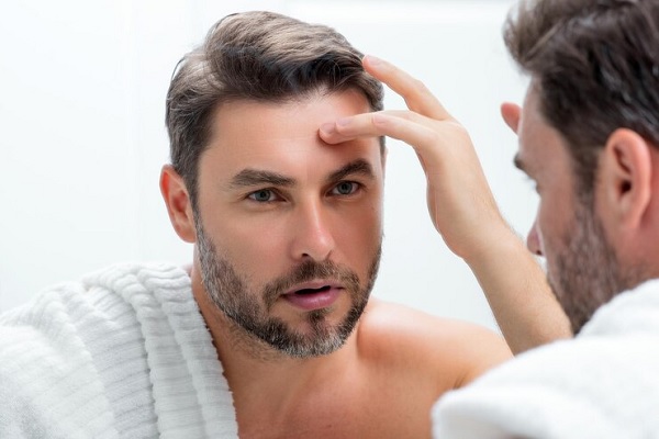 revisar el cabello- hombre joven mirando su cabellera