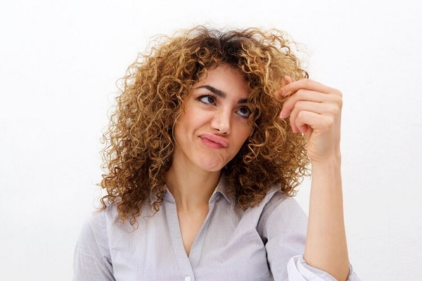 revisar el cabello- Mujer observa su pelo amarillo crespo