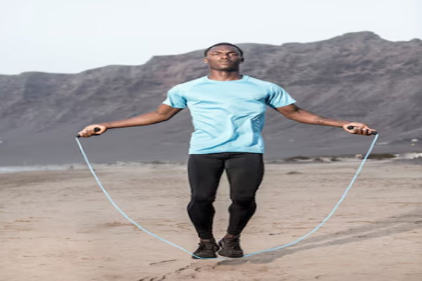 Hombre moreno saltando la cuerda en la playa