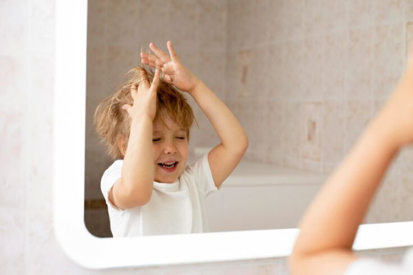 Síndrome del cabello impeinable - Niño de cabello rubio juega con su pelo frente al espejo
