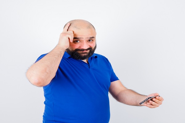 hombre calvo revisando en su teléfono información acerca del miedo a la calvicie