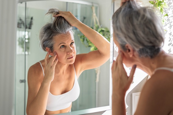 una mujer de mediana edad examinando su cabello canoso