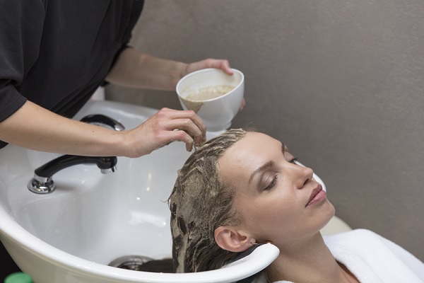 una mujer aplicándose cuidados en el cabello una estética
