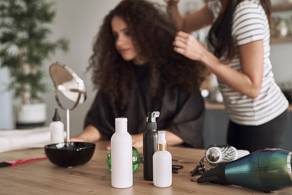 una especialista le aplica un tratamiento capilar a una mujer de cabello rizado
