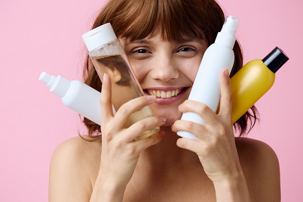 una mujer sostiene junto a su cara productos capilares