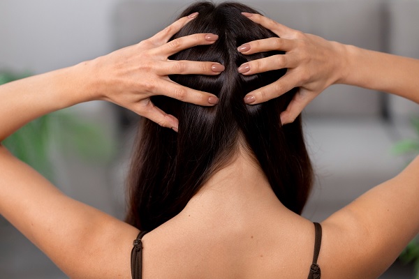 una mujer de espalda muestra su cuero cabelludo y su cabello que crece sanamente